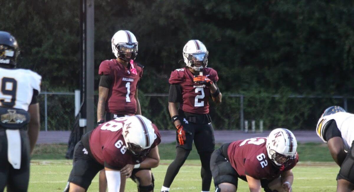 New Albany quarterback Kam Ray (1) and Ayden Burke (2) line up behind the Bulldogs offensive line.